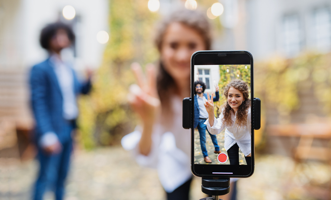 Young couple making video with smartphone outdoors on street,tik tok